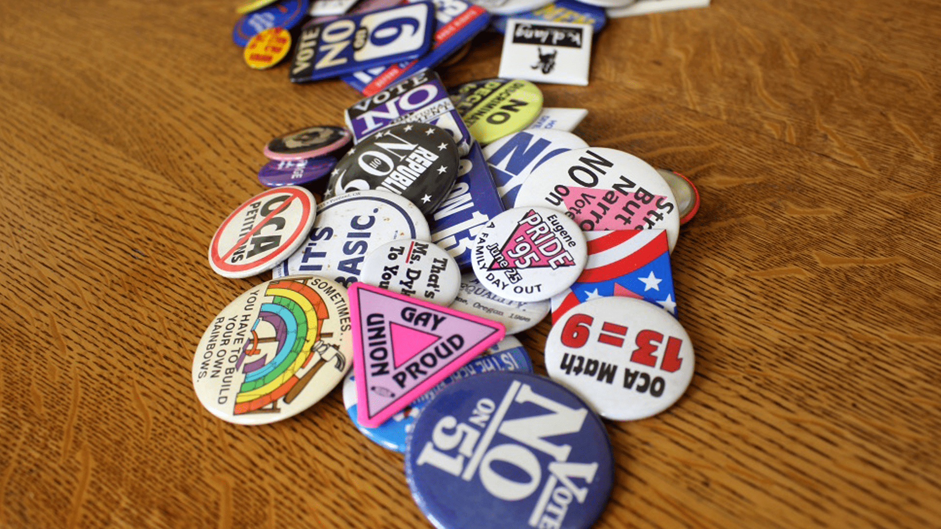 A collection of political buttons opposing local anti-LGBTQ initiatives.