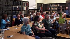The project narrators are seated together in library as audience members as they await presentation.